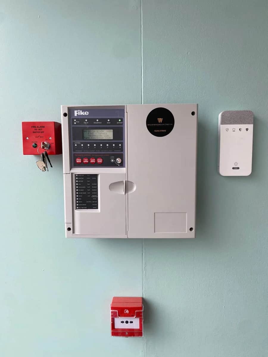 Fire alarm panel and call point mounted on a wall
