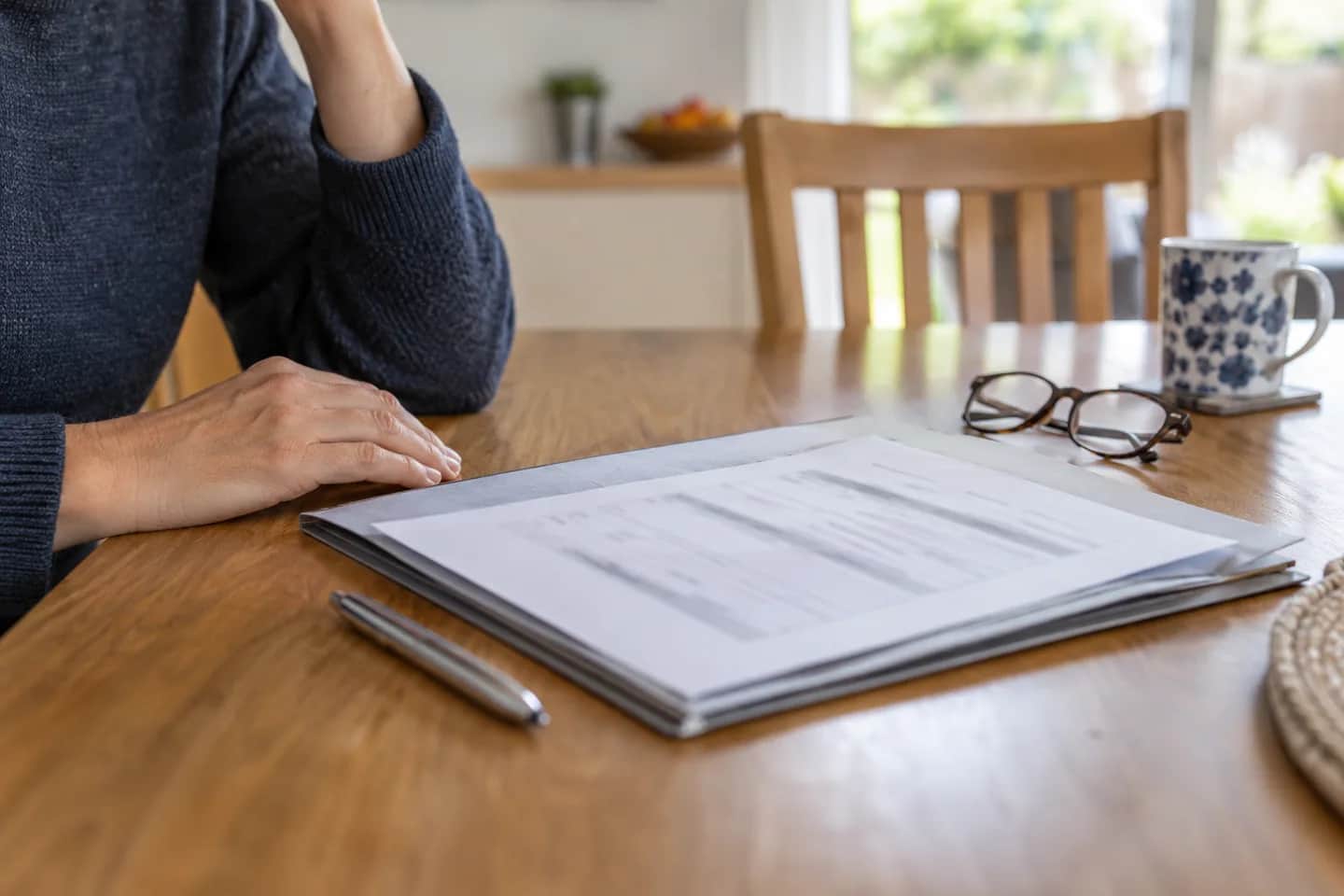 Person reviewing inspection paperwork in a folder at a dining table
