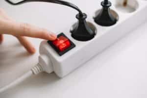 Hand turns on an electric surge protector. Protection of household