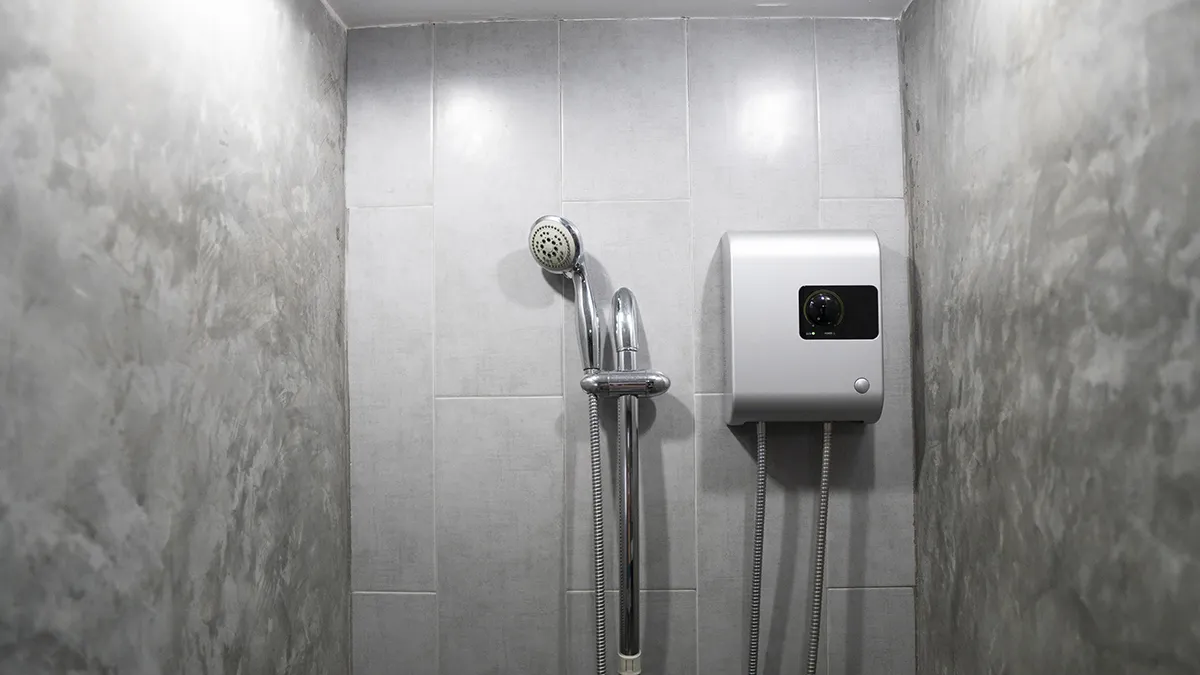 An instant tankless electric shower installed on a grey tiled wall